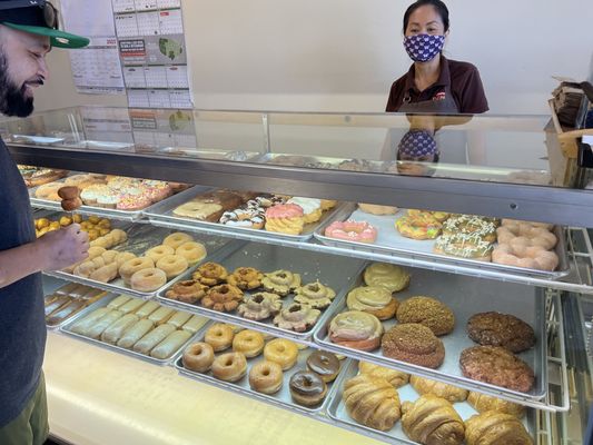 The donut display case at Family Donut, every shelf filled, with a customer at the counter