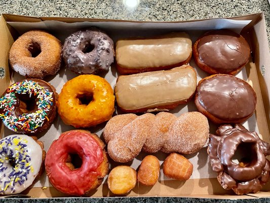 An overhead view of a full box of sixteen assorted donuts and donut holes
